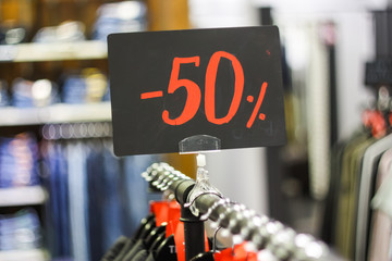 Obraz premium Close-up red tag sale 50 percent discount in a clothing store. Big reductions concept for Black Friday and Holiday season sale.