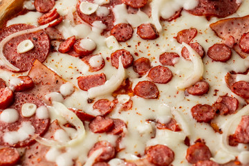 Top view of pizza with chili pepper , hot sausages, onion, ham, salami, garlic, tomatoes and cheese.