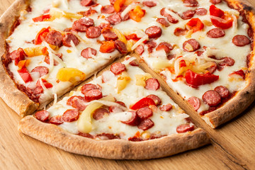 Top view of hot pizza with chili pepper , hot sausages, onion, tomatoes and cheese. 