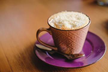 Mug of brown cacao decorated with nut crumb on a wooden table.