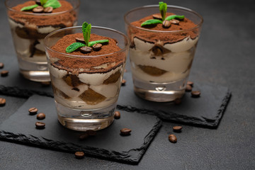 Classic tiramisu dessert in a glass on stone serving board on dark concrete background