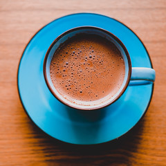 Brown cacao in bright blue mug on a wooden table.