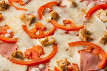 Flat lay with traditional Italian pizza with chicken, ham, cheese and tomatoes on wooden  back.