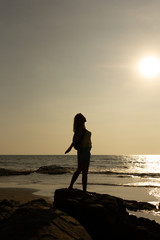 Fototapeta premium Silhouette of a young woman against the background of the sea and the sun