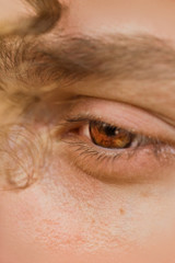 male eye close up. a curl of curly hair hangs over a man's face. thoughtful look into the void