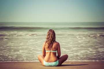Fototapeta na wymiar Young woman meditates sitting on the ocean