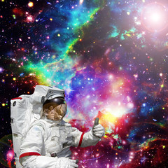 Astronaut gives thumbs-up against outer space, galaxies and stars. The elements of this image furnished by NASA.