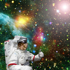 Astronaut gives thumbs-up against outer space, galaxies and stars. The elements of this image furnished by NASA.