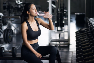 Fototapeta na wymiar Sporty girl drink water after dumbbell exercise