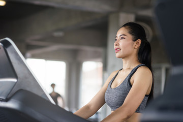 Fototapeta na wymiar Smile woman run on treadmill in gym
