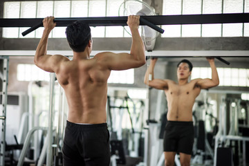 Fototapeta na wymiar Back muscle building by pulling bar in gym
