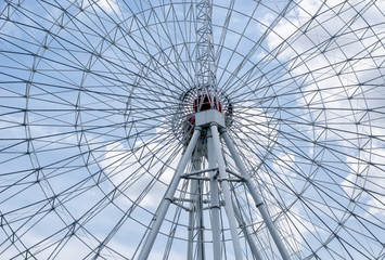 "Ferris Wheel" against a cloudy blue sky