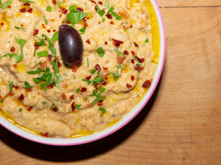Babaganoush - Meze or Turkish Appetizer in a Bowl on a Wooden Table - Eggplant Paste - Garnished with Olive, Pepper Flakes and Parsley