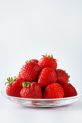 Freshly picked organic strawberries in a glass bowl. White background, water, isolated, high resolution