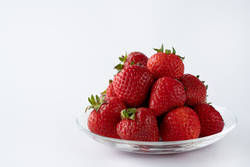 Freshly picked organic strawberries in a glass bowl. White background, water, isolated, high resolution