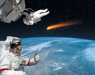 Astronaut gives thumbs-up, comet on the background. The elements of this image furnished by NASA.