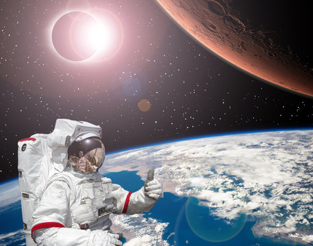 Rocket flies from earth to Mars. Astronaut shows the thumbs-up. Solar eclipse.  The elements of this image furnished by NASA.