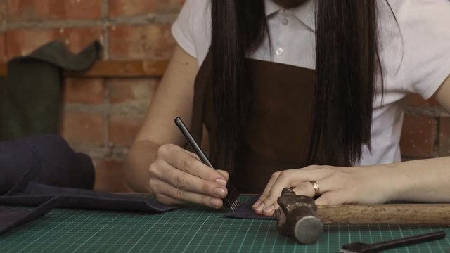 Handmade and leatherwork concept. Professional female tanner working with genuine leather at workshop in slow motion
