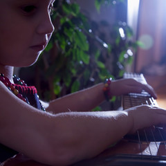 Close up little cute child girl learning to play the acoustic guitar