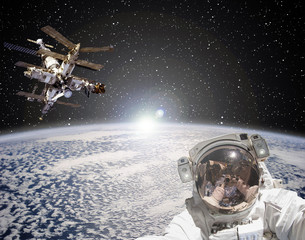 Astronaut, space station and sunrise on the backdrop. The elements of this image furnished by NASA.