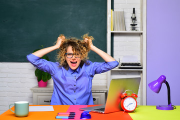 Bored teacher preparing for university exams. Screaming teacher works with laptop in classroom. Hard work. School job. Education and knowledge concept. World teachers day. Back to school. Online test.