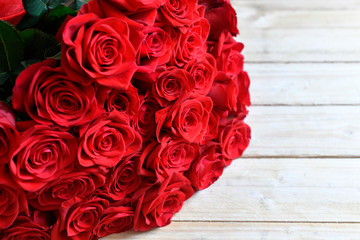 Bukiet czerwonych róż na drewnianym  stole - obrazy, fototapety, plakaty