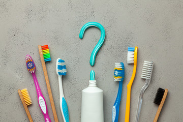 Toothpaste in the form of a question mark and many different and colored toothbrushes. Concept of how to choose the right toothbrush or how to brush your teeth
