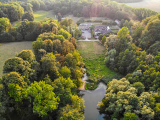 Aerial view of country side area in Walloon Brabant, Belgium. Luxury villas with garden surrounded by forest and small lake during autumn season