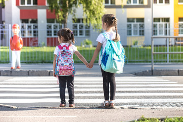 Back to school education concept with girl kids, elementary students, carrying backpacks going to...
