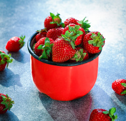 .red strawberry in a red mug on a blue background