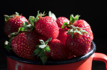 .red strawberry in a red mug on a black background
