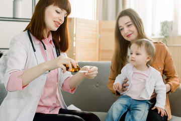 Doctor giving a spoon of syrup to little kid girl
