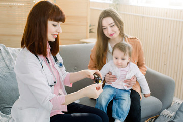 Little baby girl accepts to drink medicine syrup with spoon from family doctor at home.