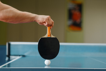 Male person hand with racket and ping pong ball