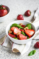 Fresh spinach salad with strawberries and nuts on a gray background. Summer salad with strawberries