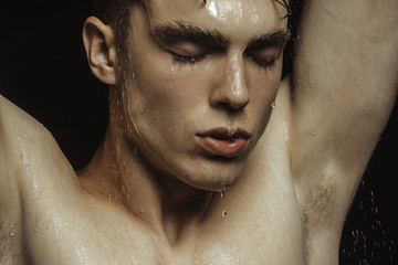 Handsome wet sport sexy stripped guy portrait with waterdrops and smoke on isolated black background