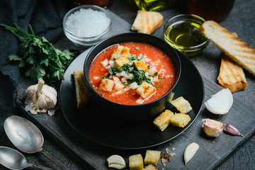 Traditional spanish gazpacho made from fresh farm produce on a dark background.