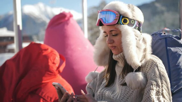 Happy woman in ski resort sitting in the cafe and texting with her friends in the social network, shares his impressions of the rest.