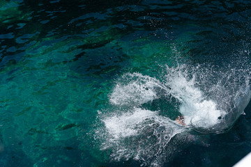 High angle view on the splash in the sea after man woman jump in water ocean in summer day lake