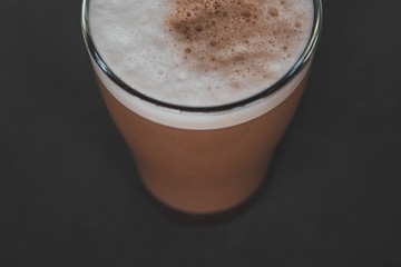 A large transparent glass filled with cold summer drink with milk and green tea powder is photographed on a gray, isolated background, photo for the menu