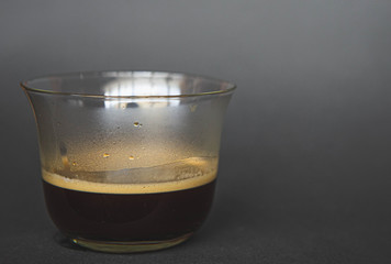 large transparent glass filled with of aromatic espresso coffee photographed on the isolated gray background picture for the menu.