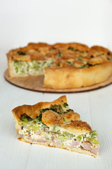 a piece of cake on a plate is photographed against the background of a whole pie from which cut a piece, a stylish photo of a pie on a white wooden background