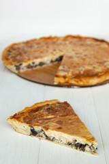 a piece of cake on a plate is photographed against the background of a whole pie from which cut a piece, a stylish photo of a pie on a white wooden background