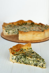 a piece of cake on a plate is photographed against the background of a whole pie from which cut a piece, a stylish photo of a pie on a white wooden background