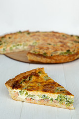 a piece of cake on a plate is photographed against the background of a whole pie from which cut a piece, a stylish photo of a pie on a white wooden background