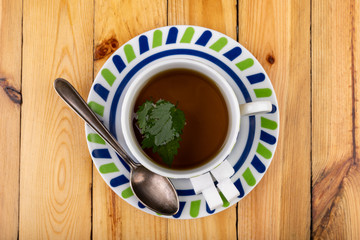 Tasty nettle tea in a cup. Freshly cut nettle and infected tea on a wooden table.