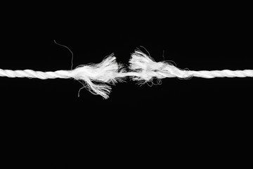Tearing the rope in the middle of the frame on black background - obrazy, fototapety, plakaty