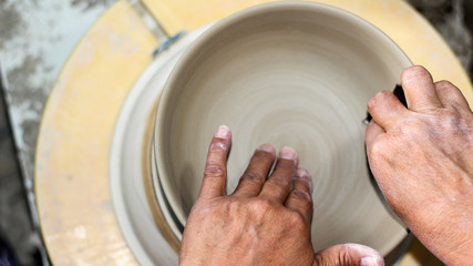 hands of a potter, creating an bowl on the circle, Pottery polishing process with 2 hands in the final step. Before entering the kiln.