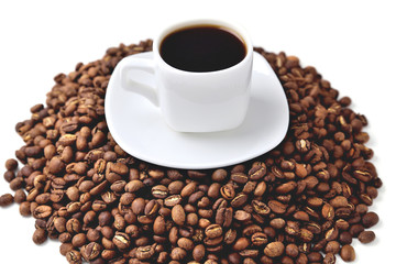 white cup of coffee on a white saucer stands on a hill of coffee beans on a white background  angle view from above