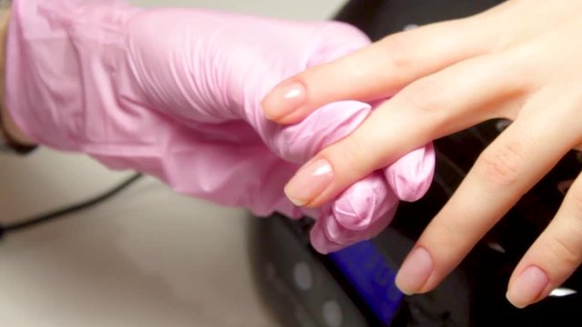 Nail Care And Manicure concept. Closeup Manicurist hands in pink gloves is Painting black Nail Polish On Client's Nails. Woman In Beauty Salon